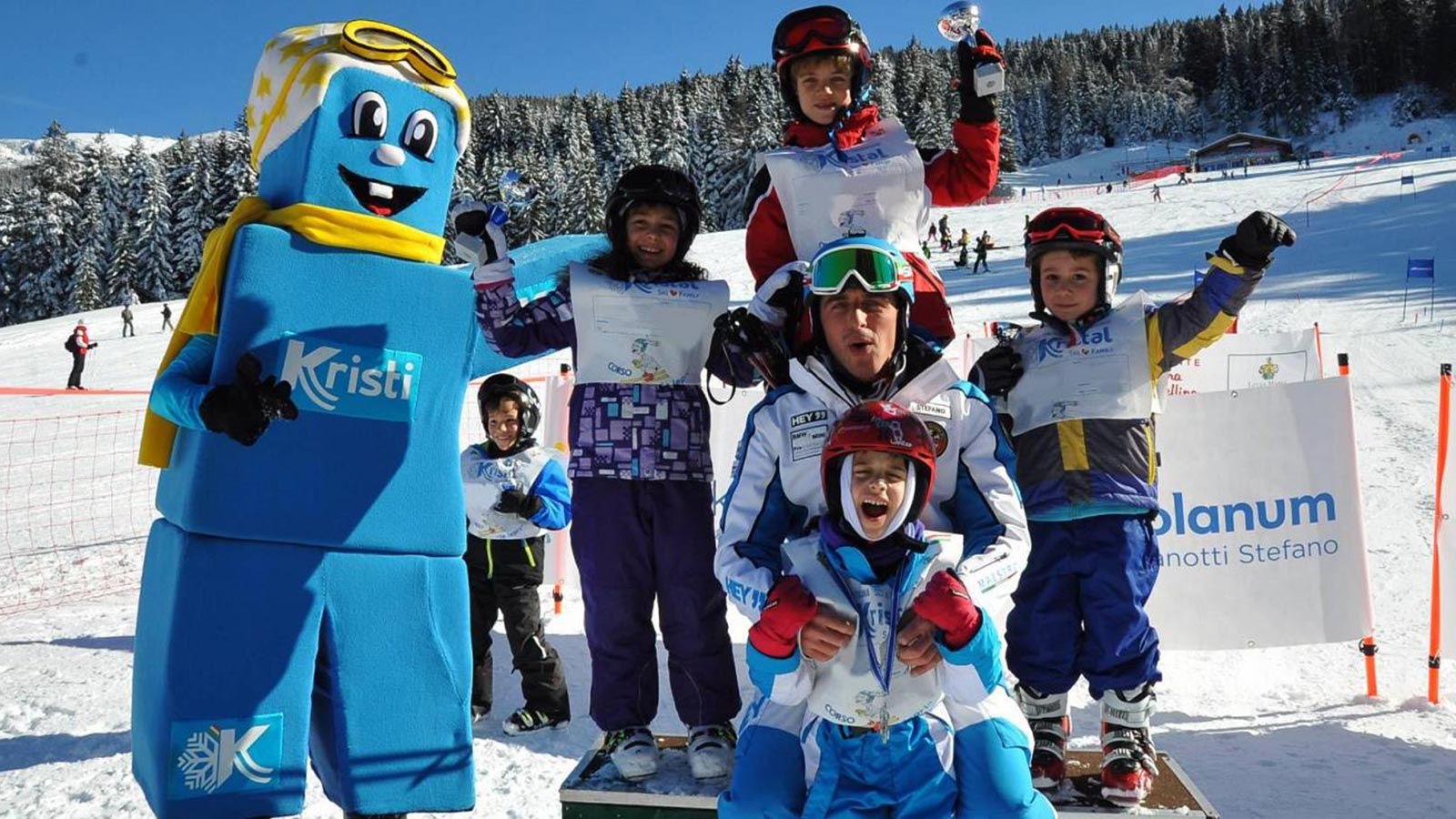 Alcuni bambini con il maestro di sci insieme alla mascotte Kristi ad Andalo in Trentino